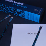 A box of Blackwing Volume 2 (Set of 12) art paintbrushes next to a white notepad.