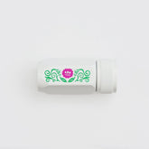 A white cylindrical pencil sharpener with a textured screw-on cap, featuring a decorative green scroll pattern and a pink flower graphic on the side, set against a plain white background.