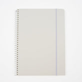 A large minimalist spiral-bound notebook by Blackwing with a white cover, a thin white elastic band, and a white wire coil binding, shown on a clean white background. It features a 'B' Blackwing emblem in the bottom-right corner.