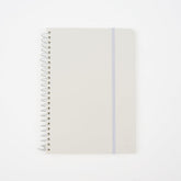 A minimalist spiral-bound notebook by Blackwing with a white cover, a thin white elastic band, and a white wire coil binding, shown on a clean white background. It features a 'B' Blackwing emblem in the bottom-right corner.