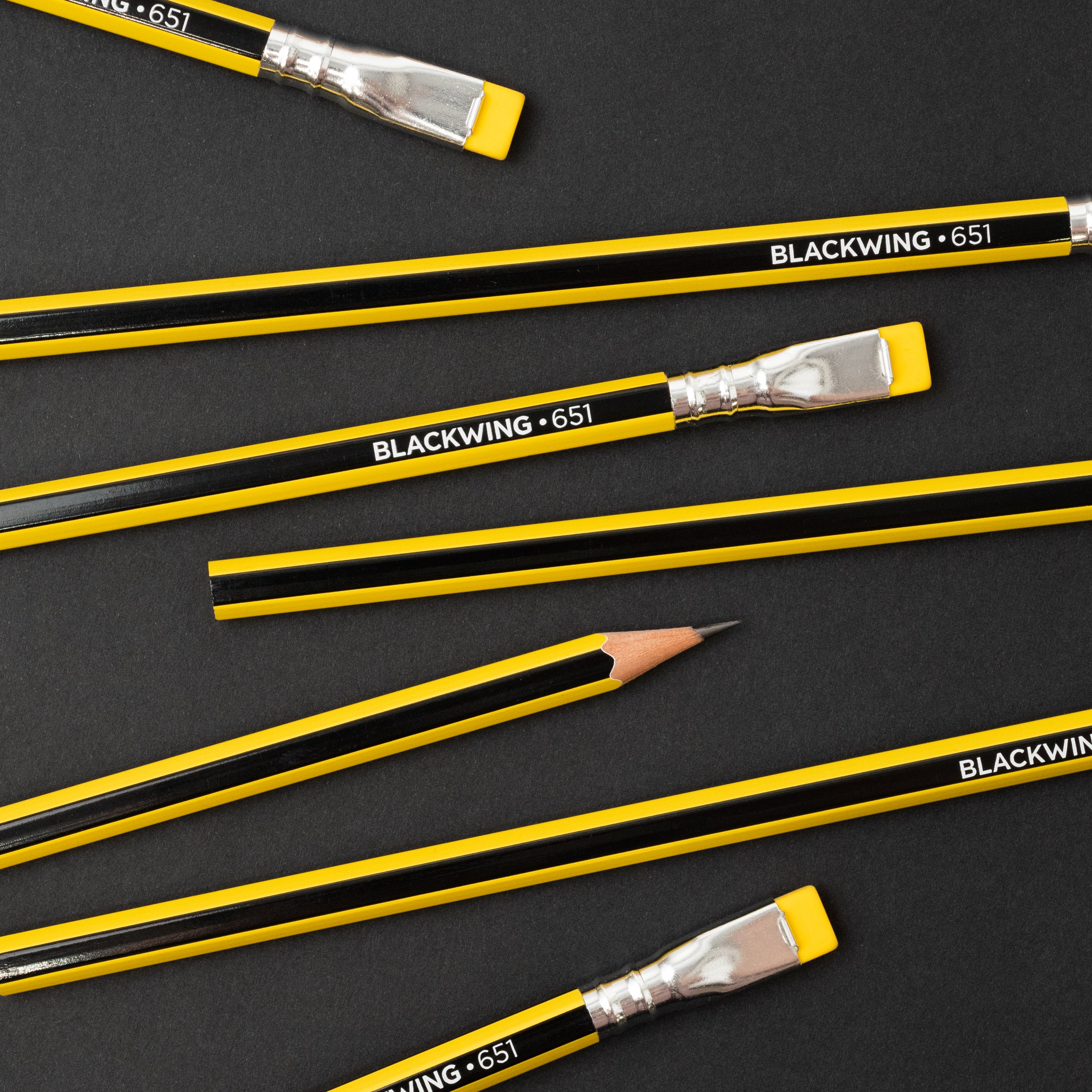 A group of yellow and Blackwing Volume 651 pencils on a dark surface.