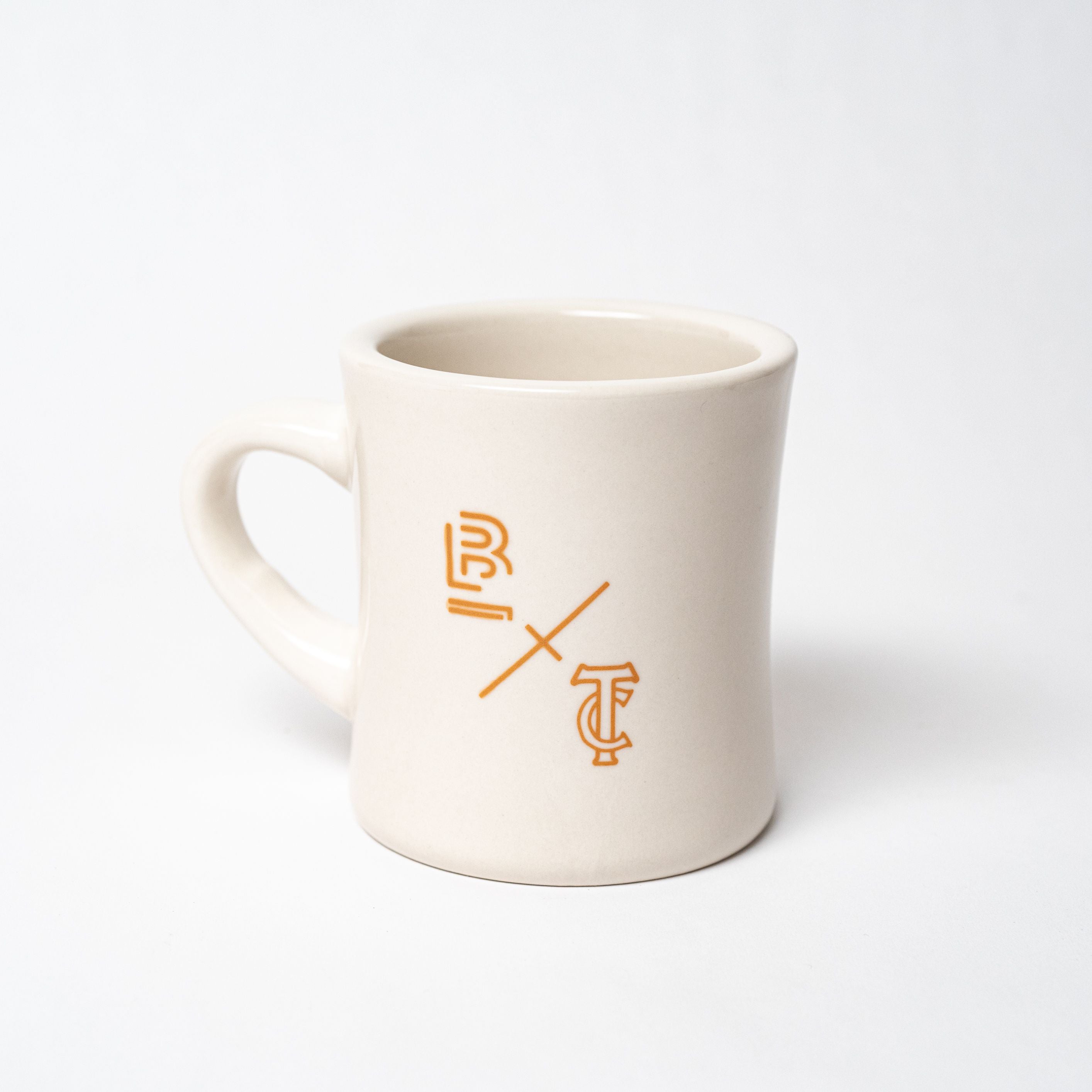 A white Blackwing x Timeless Coffee Mug with an orange Oakland logo.