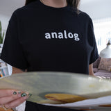 A person holding an Analog T-Shirt.