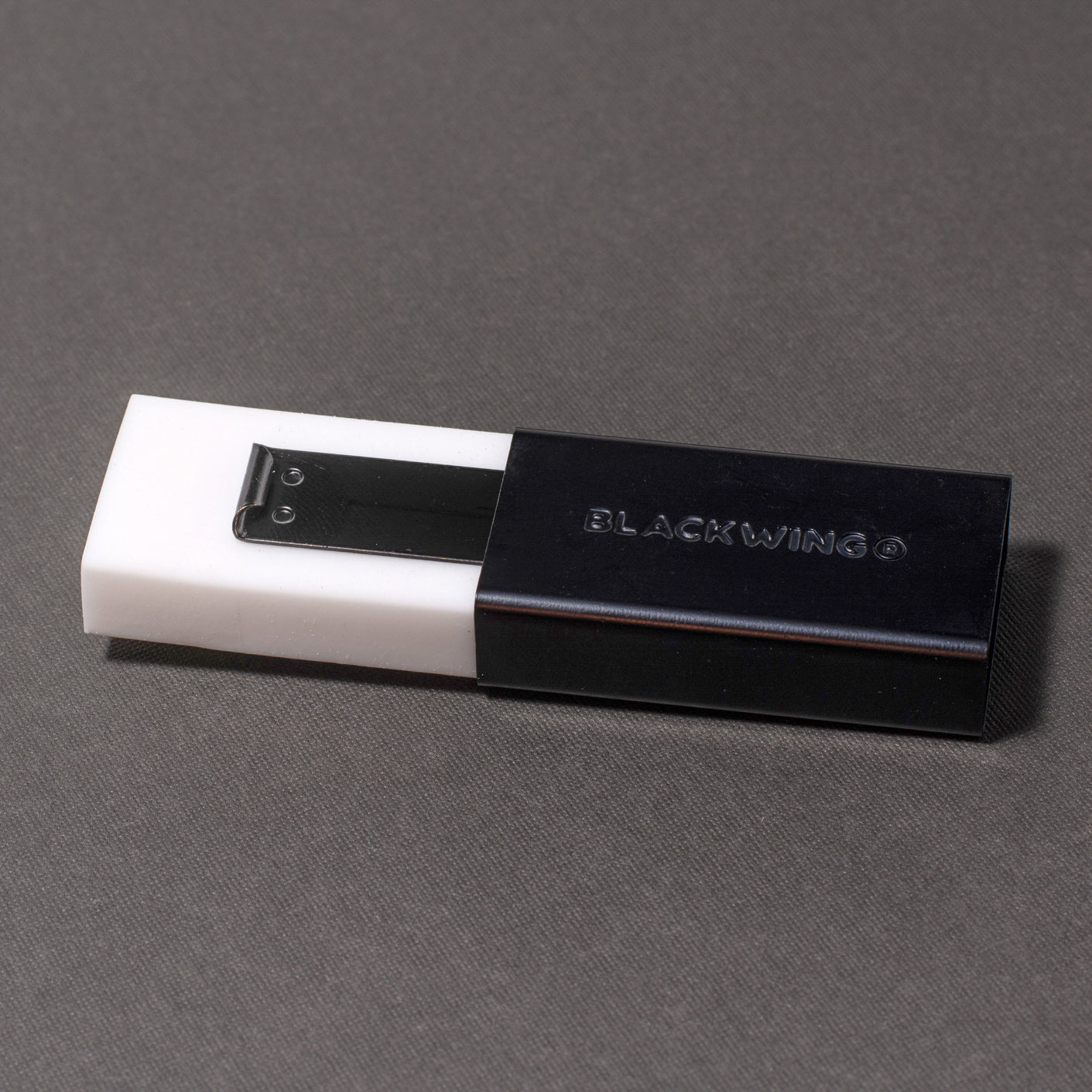 A Blackwing Soft Handheld Eraser + Holder sitting on a grey surface.