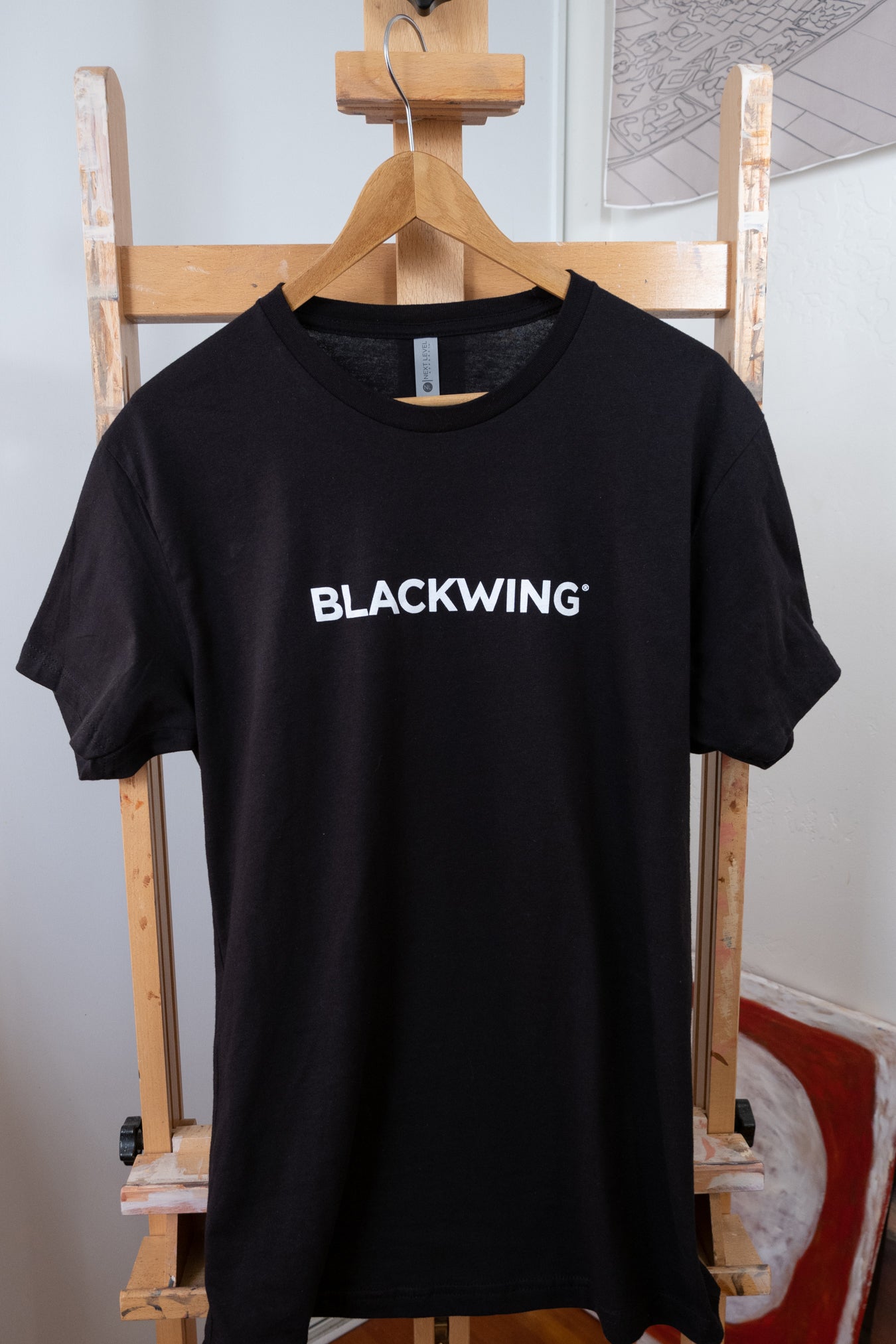 A Blackwing Logo Shirt hanging on an easel in California.