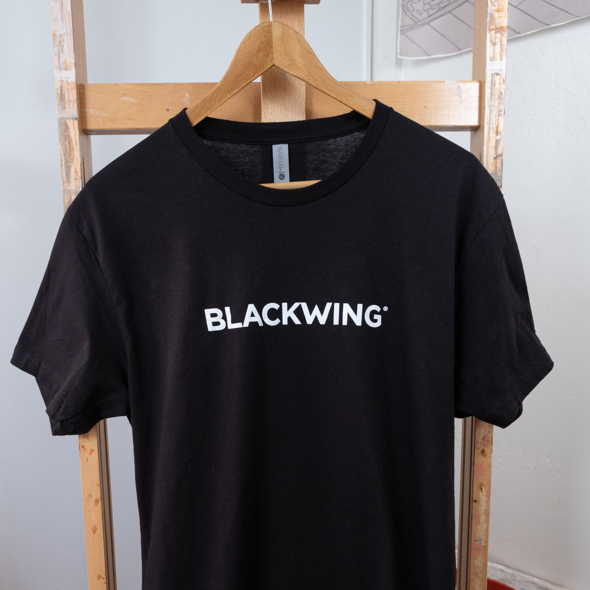 A Blackwing Logo Shirt hangs on a rack.