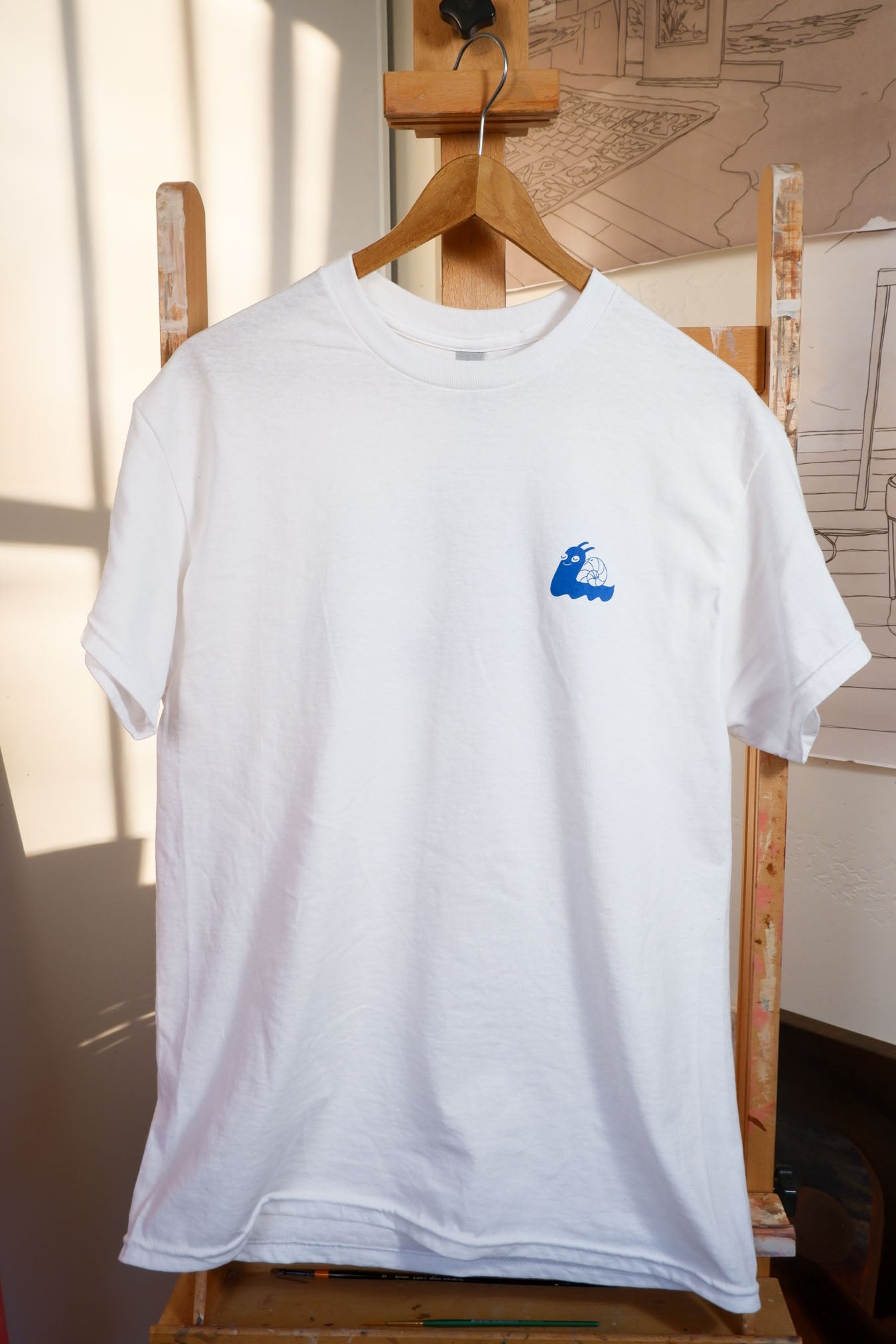 A white "Slow Down" T-shirt with a blue wave design, perfect for a casual look.