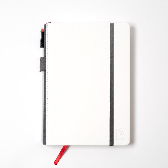 A Blackwing x Timeless Coffee Slate Notebook on a white surface with a sleek black pen.