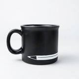 A Blackwing Coffee Mug with a pencil resting on it.