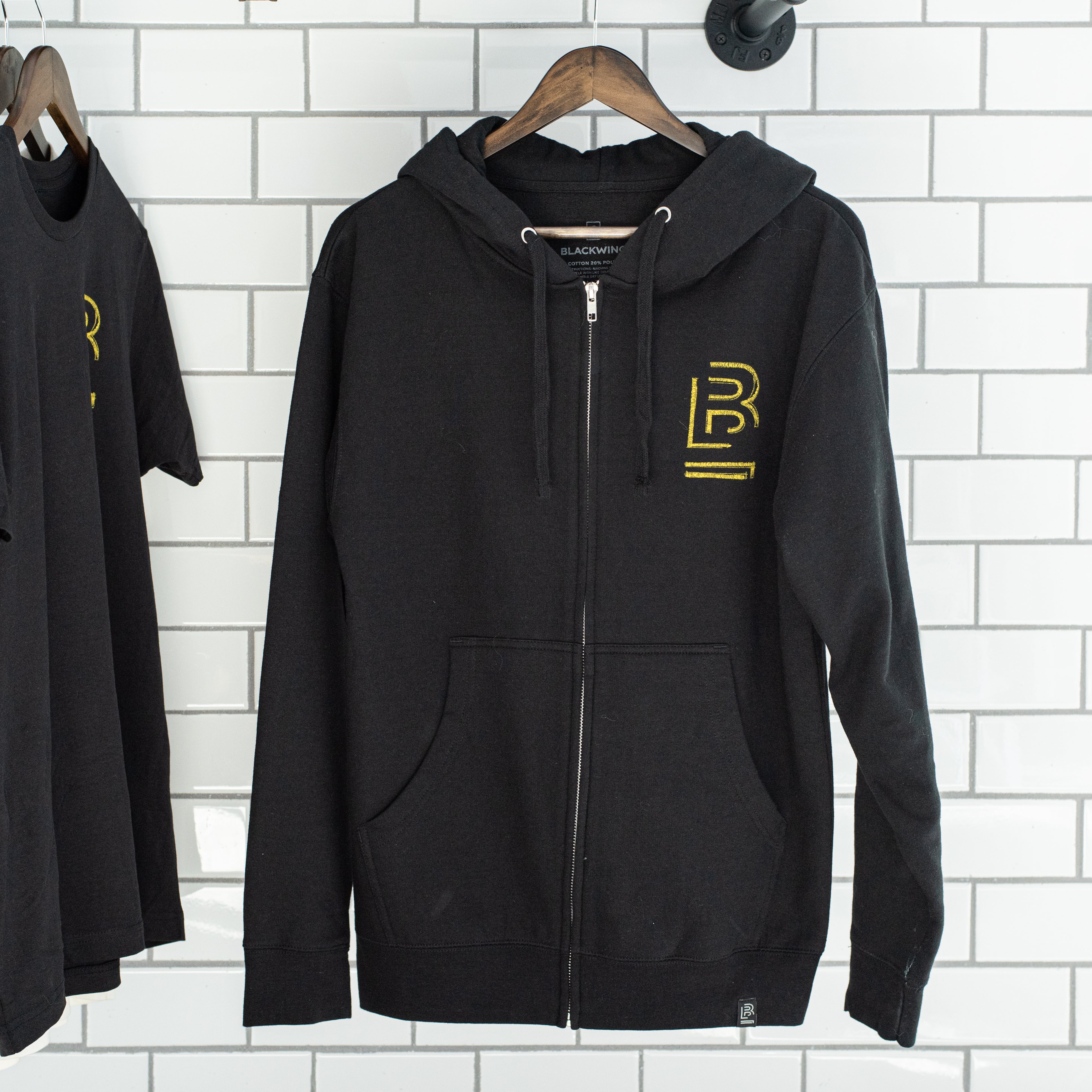 Two Blackwing Sketch Zip-up Hooded Sweatshirts from the Winter 2019 collection, hanging on a brick wall.