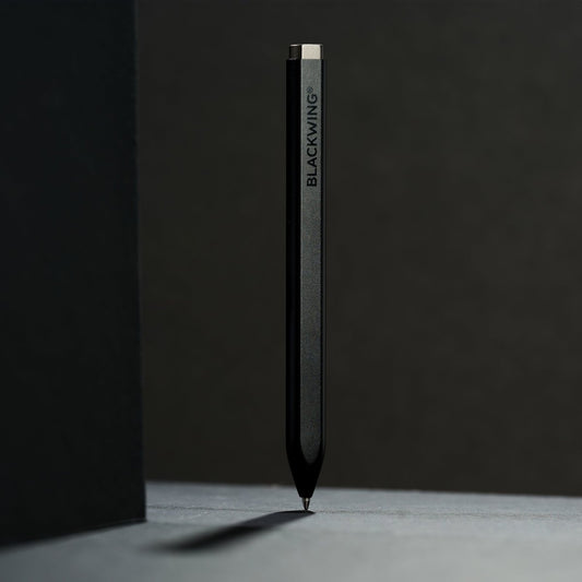 matte black pen standing vertical against a black, backlit background