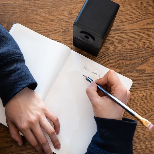 person writing in notebook with a pencil