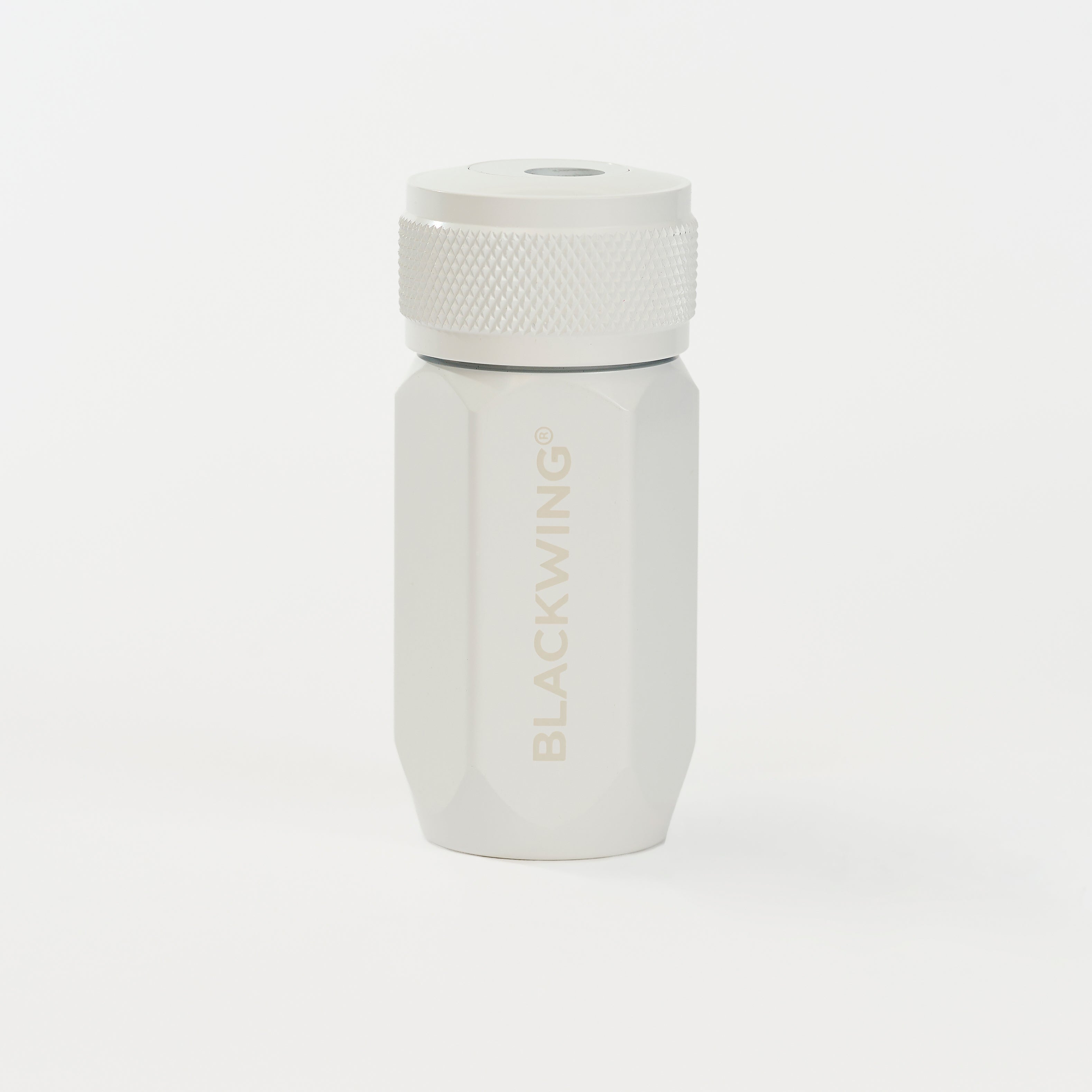 A white pencil sharpener, featuring the brand name 'BLACKWING' subtly printed on the front, set against a seamless white background.