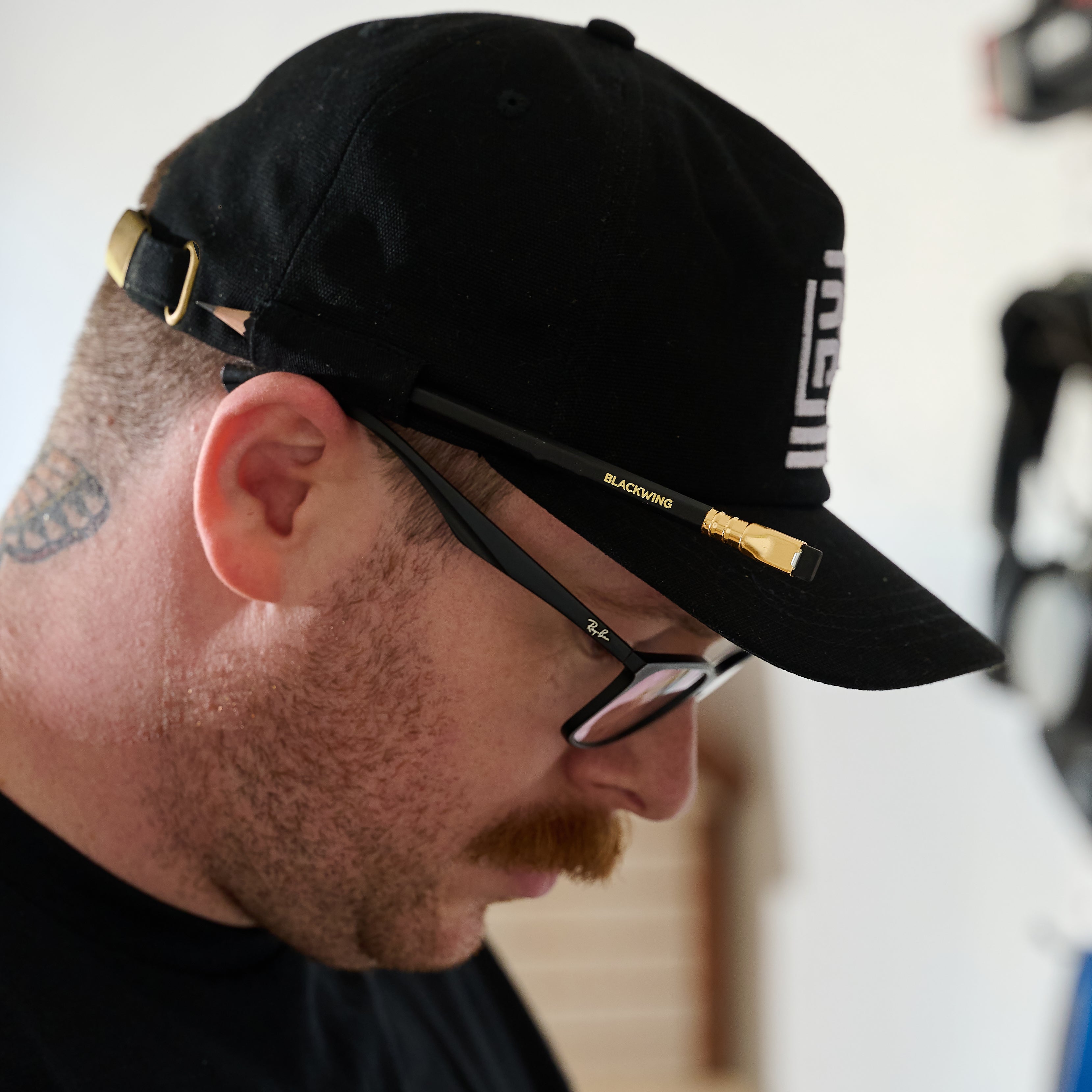 Side profile of a man wearing a Blackwing cap that features a stitched loop on the side with a Blackwing Matte pencil.