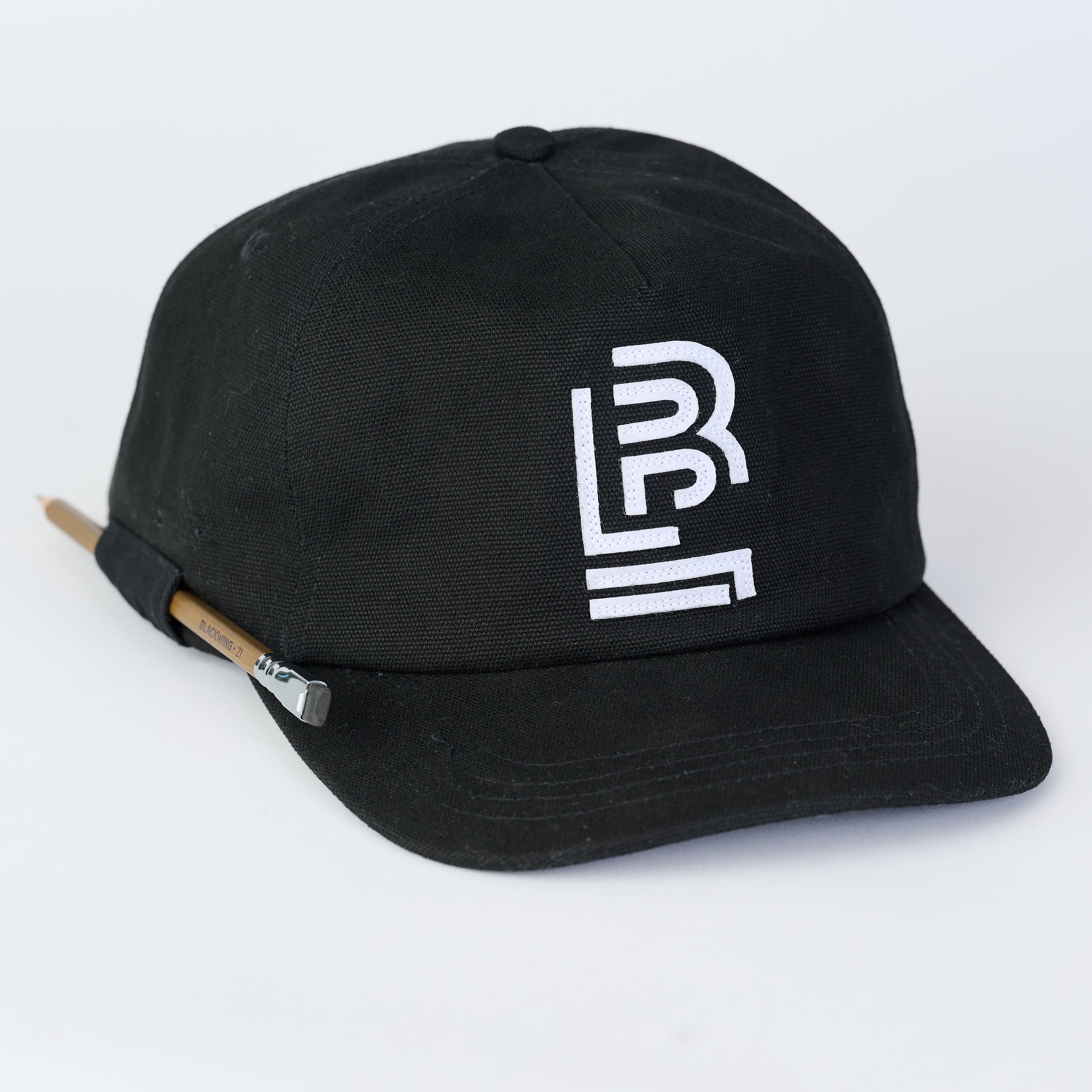 Black canvas cap with white Blackwing emblem embroidered on the front. Features a loop on the side to hold a pencil.