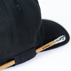 Black cap with a pencil loop on the side, holding a Blackwing volume 21 pencil.
