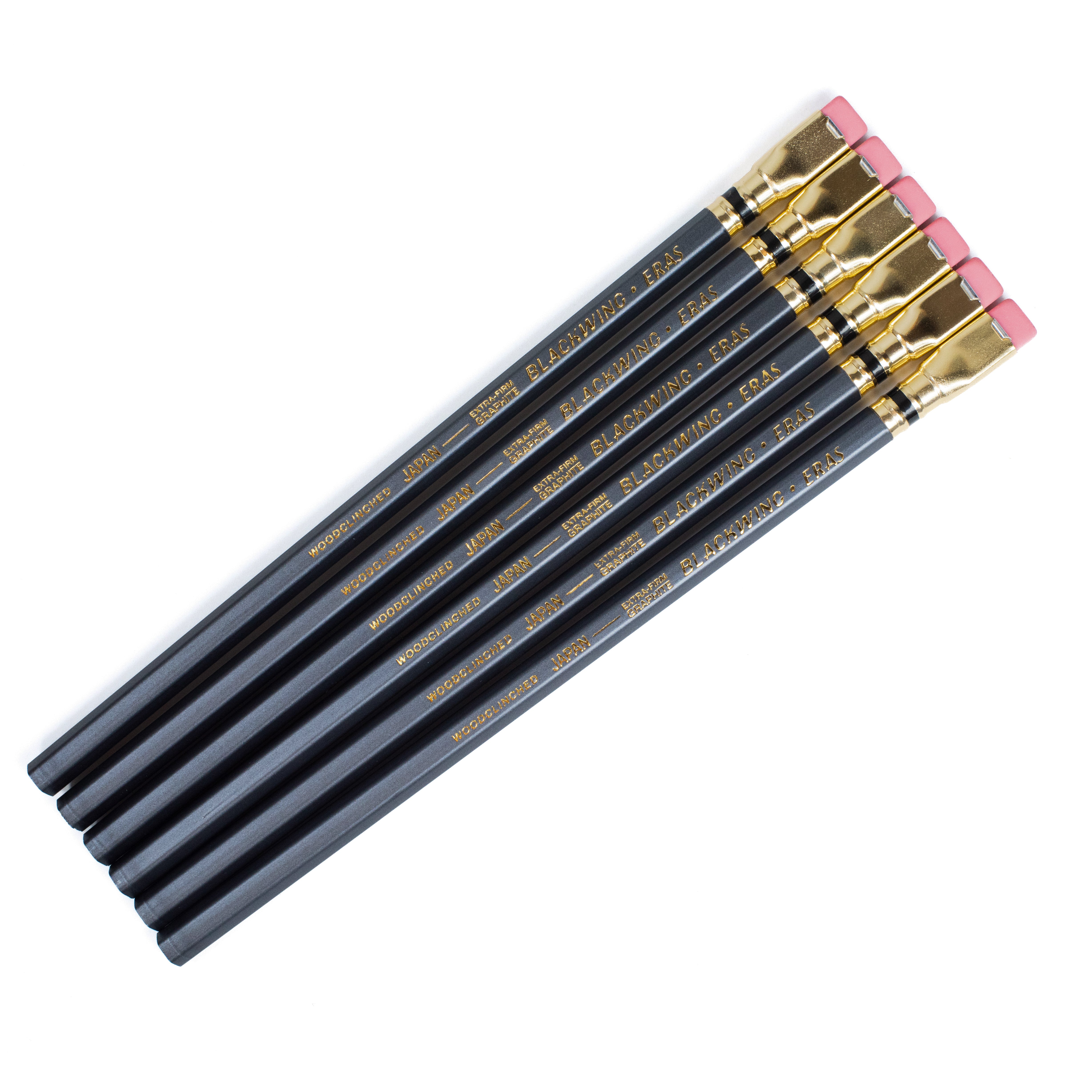 Six dark grey pencils with gold lettering and pink erasers, arranged diagonally on a plain white background.