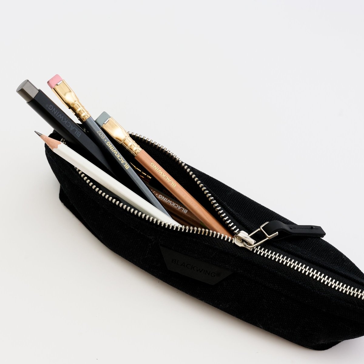 Blackwing pen and pencils inside of a black zippered pencil pouch