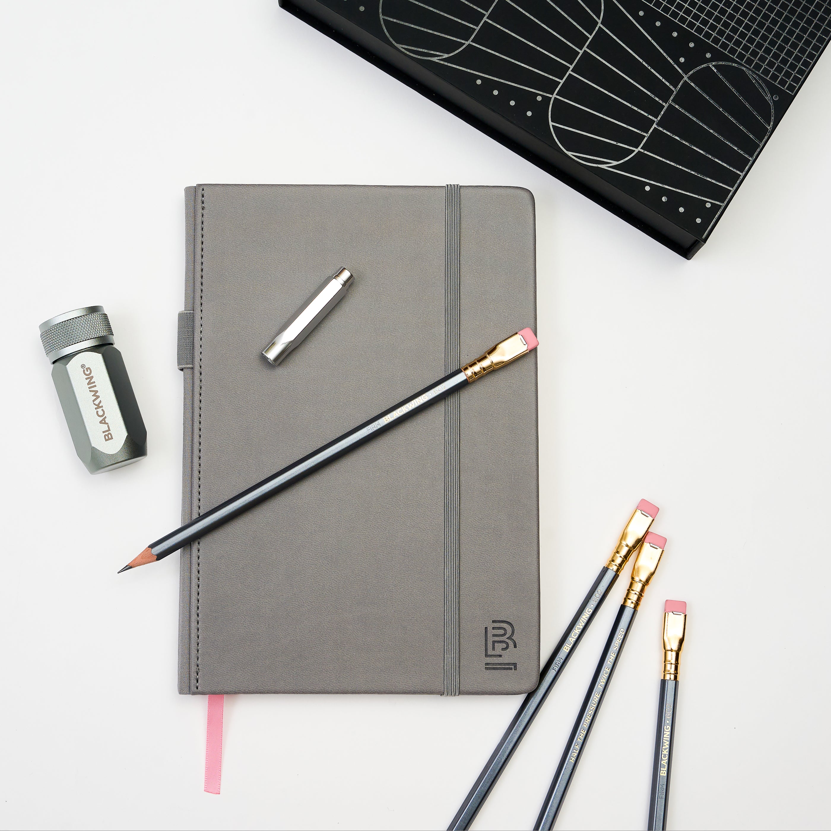 Blackwing grey hardcover notebook, 602 pencils, silver one-step sharpener, and silver point guard