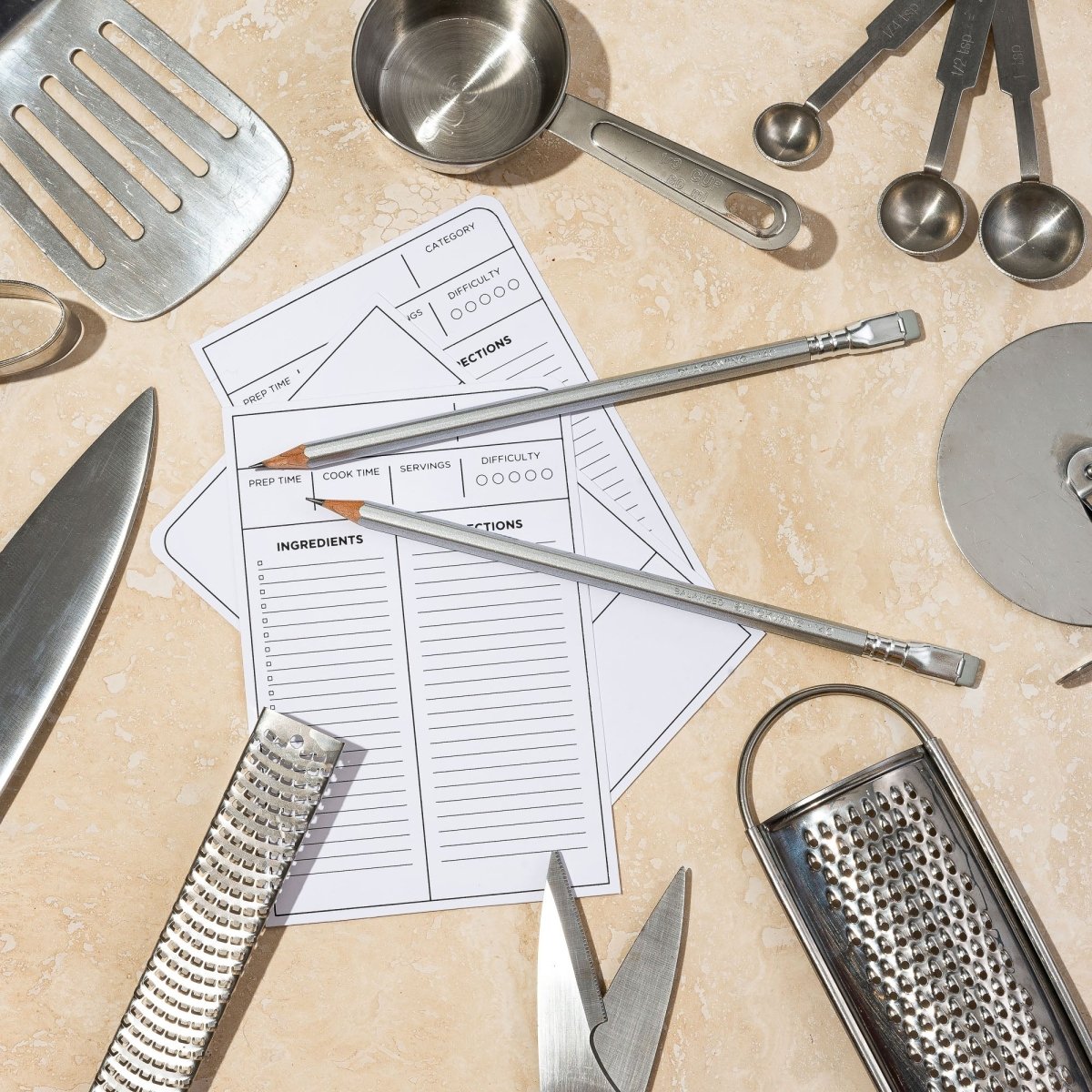 Blackwing culinary pencils sitting on a counter with recipe cards and kitchen utensils