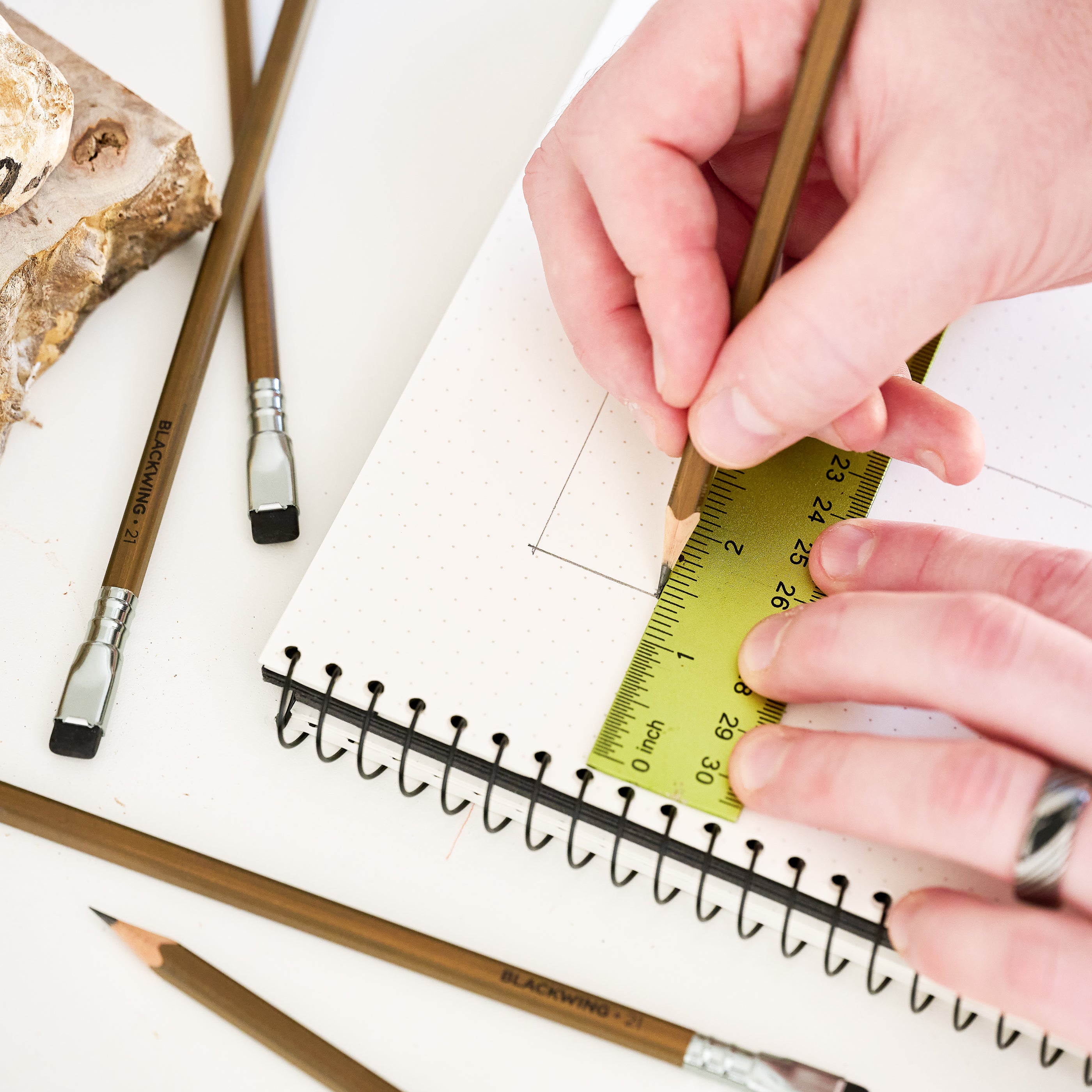 Person using a ruler and Blackwing pencil on a notebook