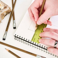 Person using a ruler and Blackwing pencil on a notebook