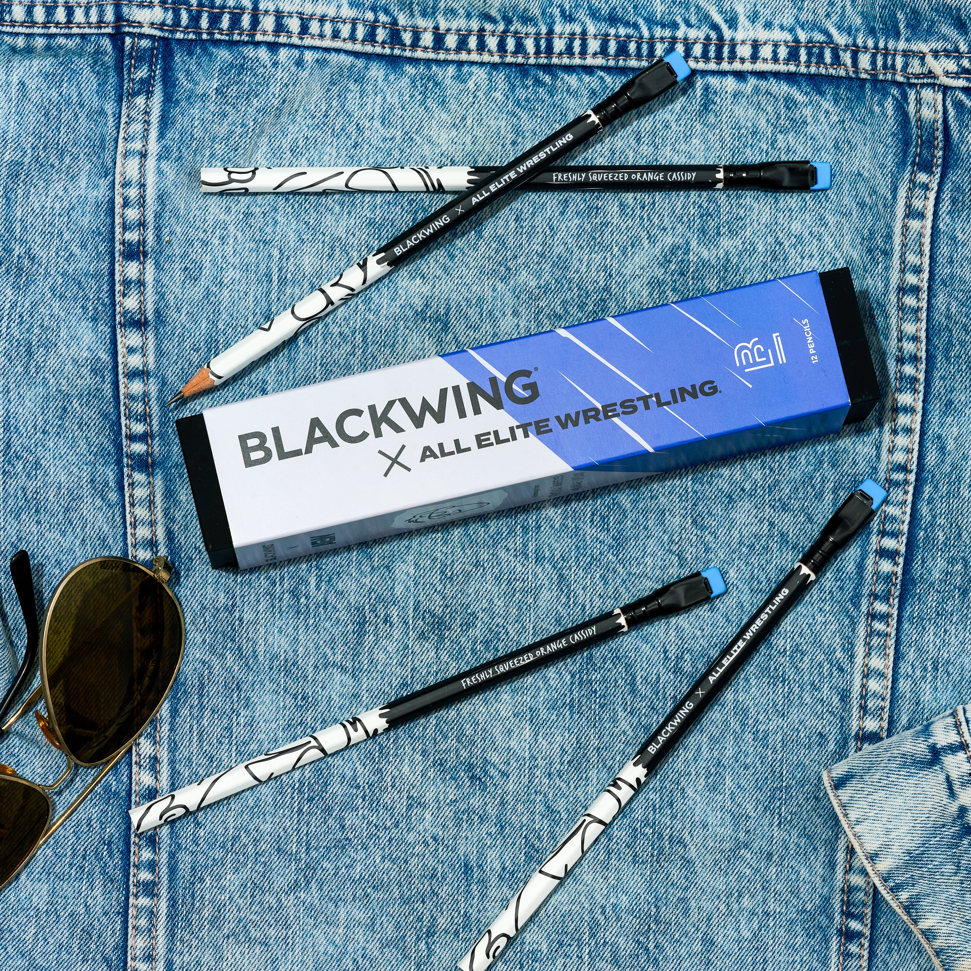 Blackwing x All Elite Wrestling pencils next to sunglasses on to of a denim jacket 