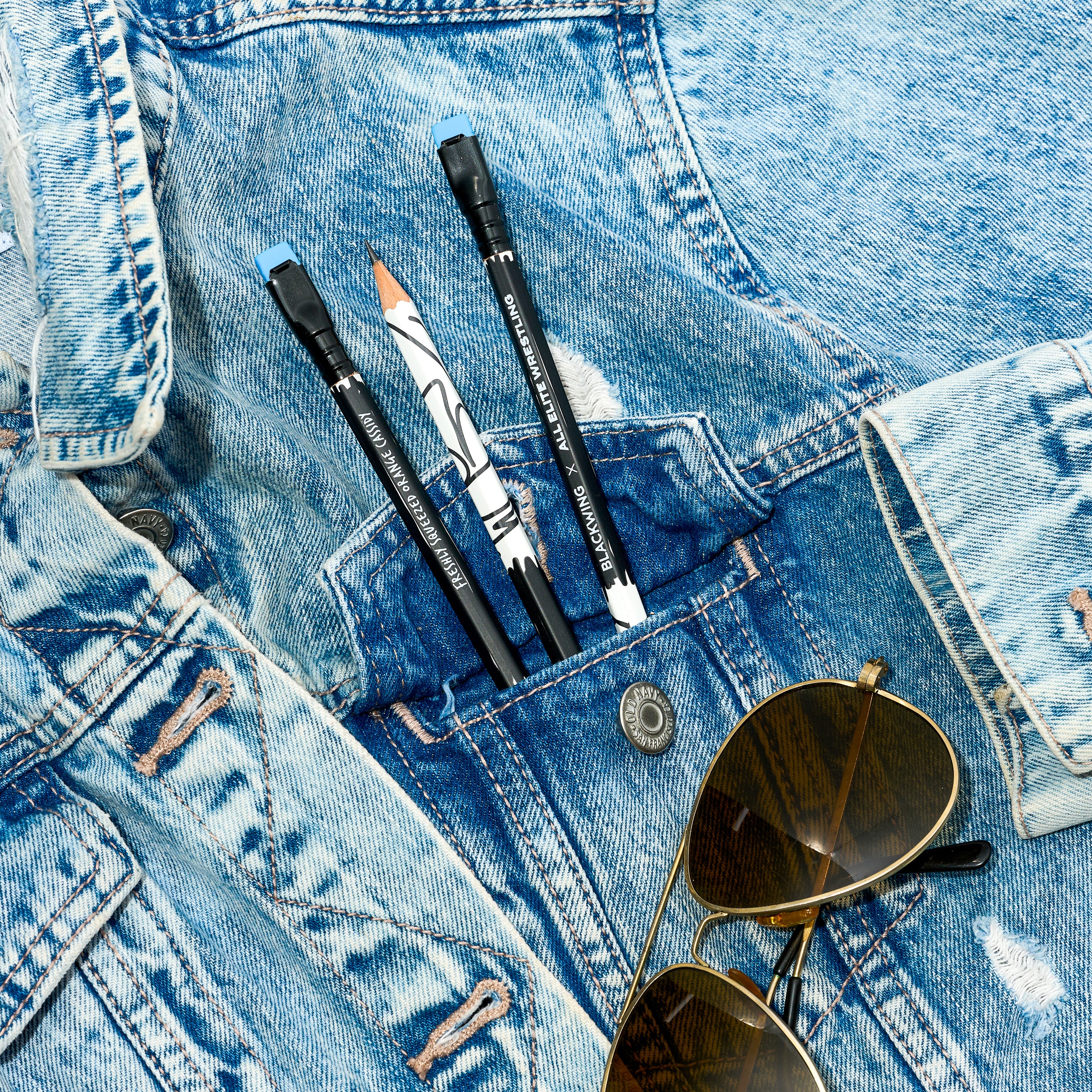 Blackwing x AEW pencils inside a denim jacket pocket with sunglasses below