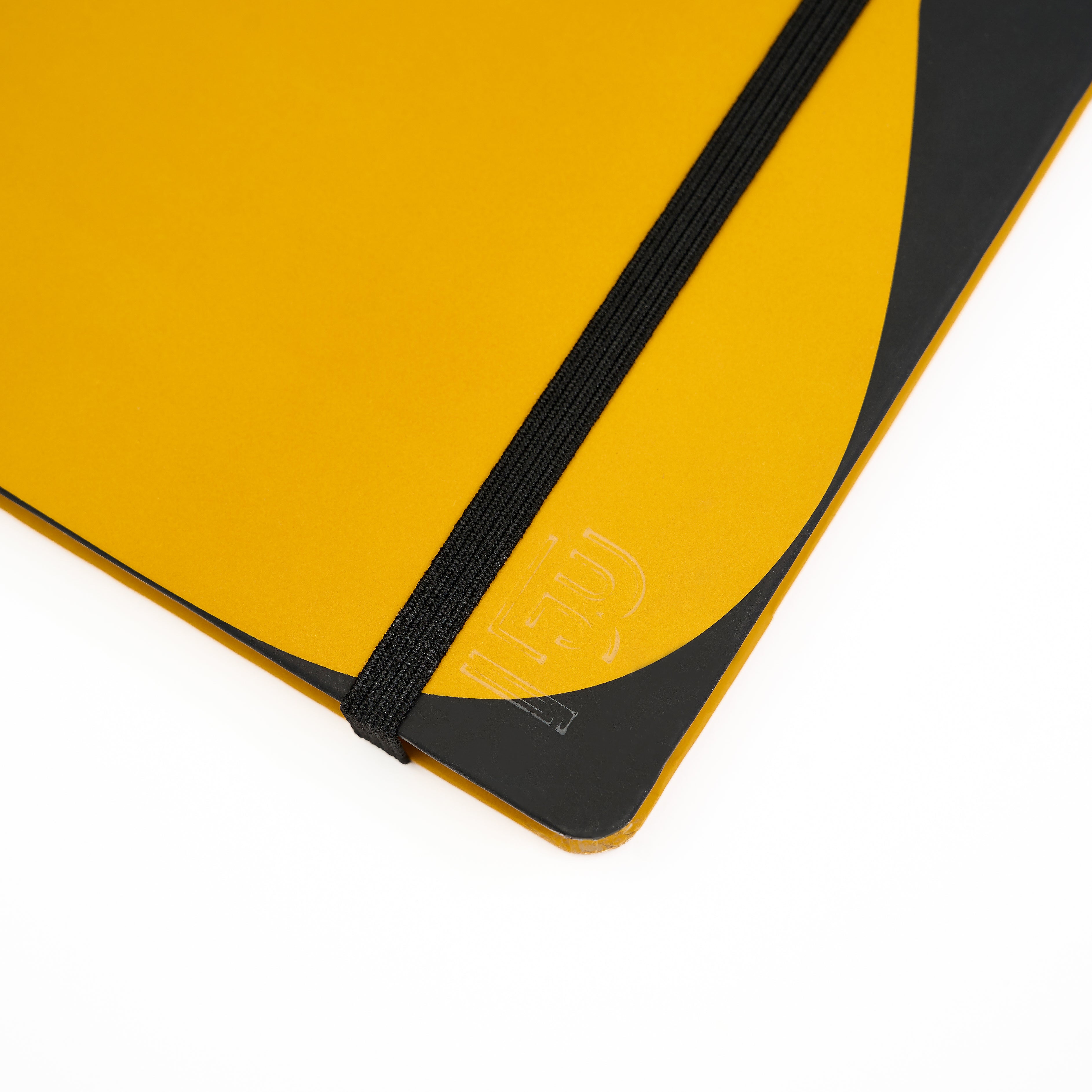 Close-up of a yellow and black notebook cover with a black elastic closure band and a debossed Blackwing emblem on a white background.
