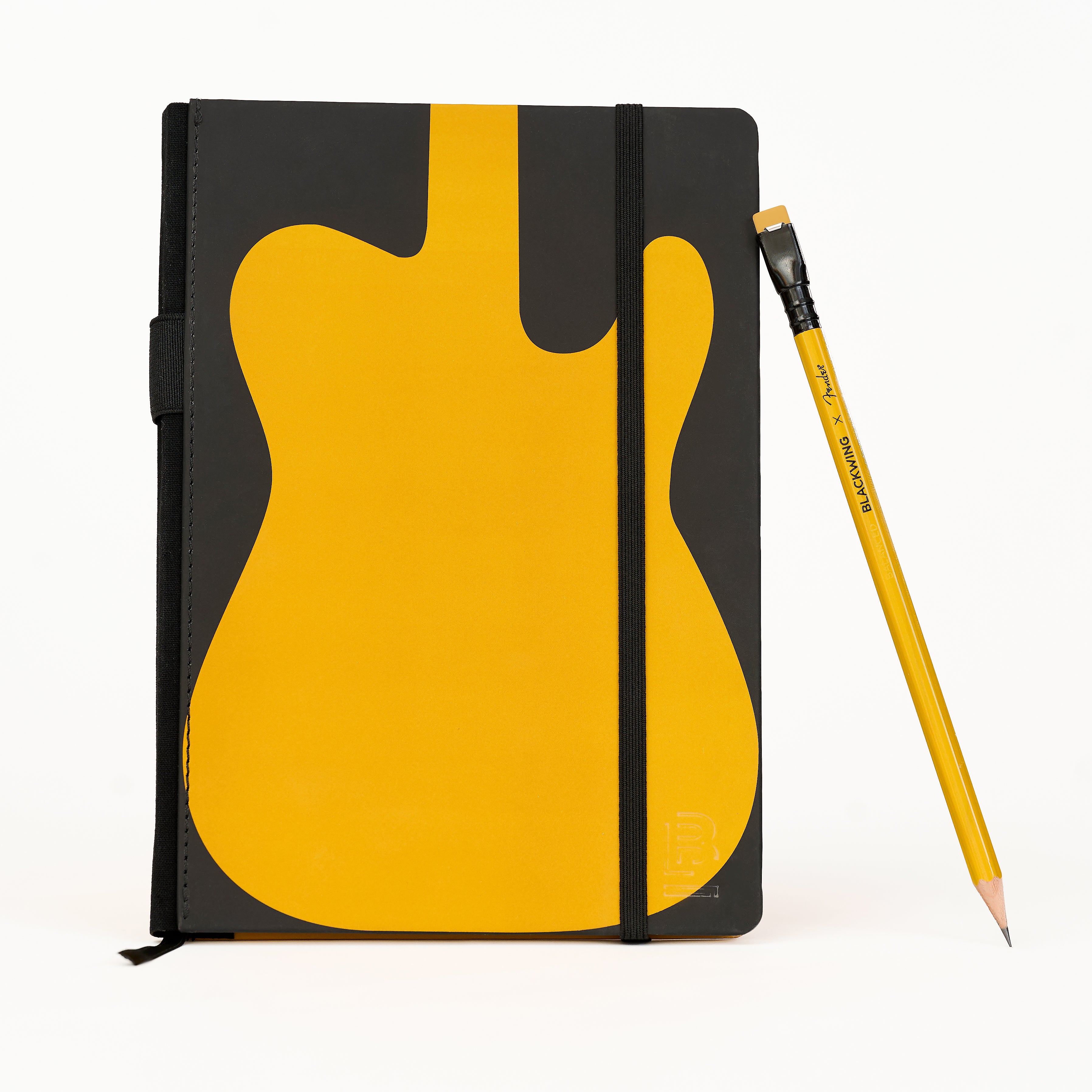 A black notebook with a large yellow guitar graphic on the cover, shown standing upright next to a yellow pencil on a clean white background.