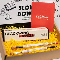 Box containing Blackwing Volumes pencils and a Keith Haring coloring book on a white background.