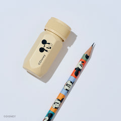 A Disney pencil and pencil sharpener set on a light gray background. The sharpener is a light beige aluminum hexagonal tool with a black Mickey Mouse graphic and the Disney name. The pencil barrel features various Mickey Mouse face graphics in different colorblocks.
