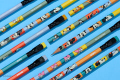 A set of colorful Blackwing Disney wood pencils arranged diagonally on a bright blue background. The pencils feature cartoon character prints including Mickey Mouse, Minnie Mouse, Pluto, and Goofy, with black erasers and black ferrules.