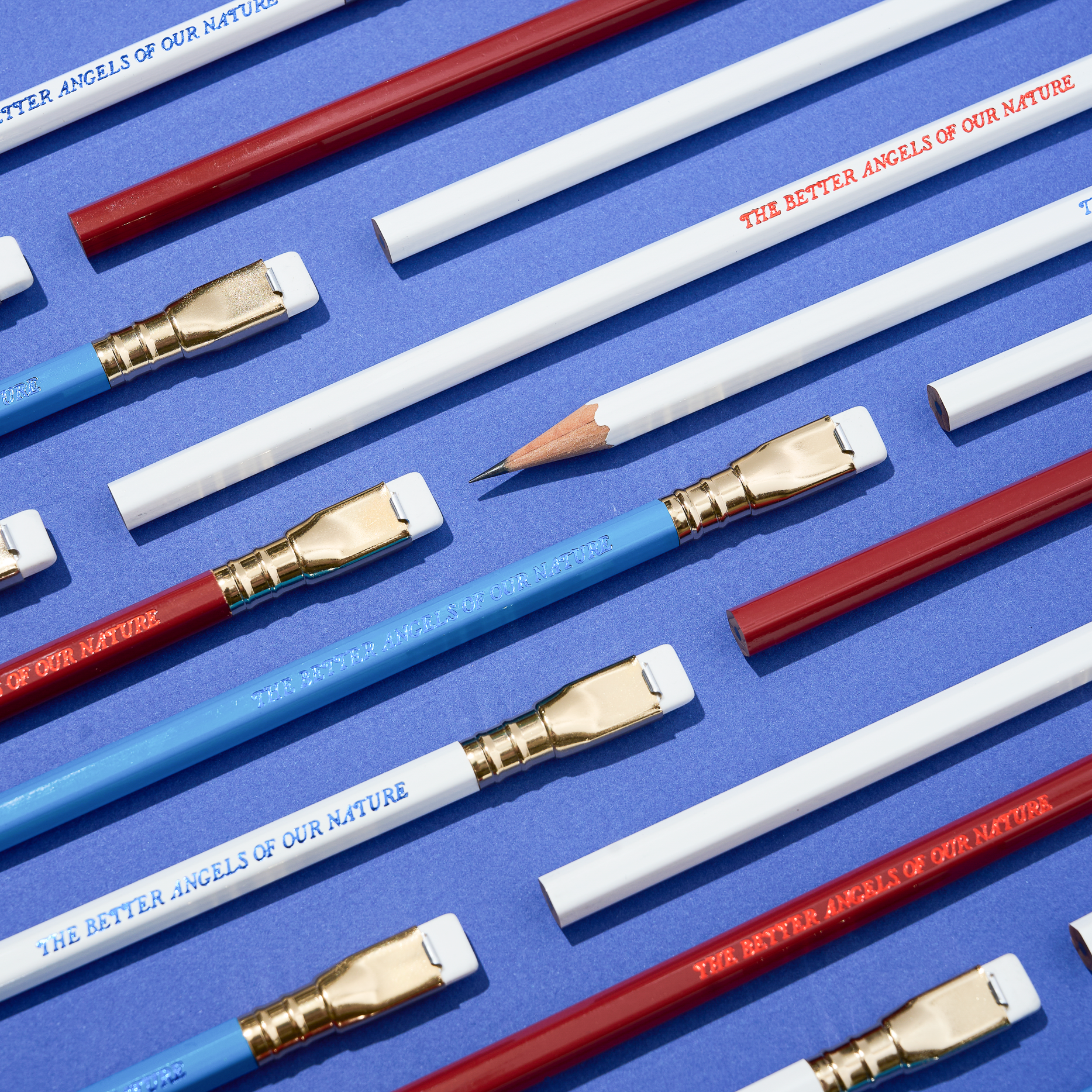 pencils that say 'THE BETTER ANGELS OF OUR NATURE' in red, white, and blue colorways arranged on a blue background