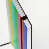 Close-up of a notebook with colorful cover and a black elastic band keeping it closed on a white background