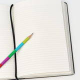 lined notebook laying open with a sharpened colorblock pencil on top.