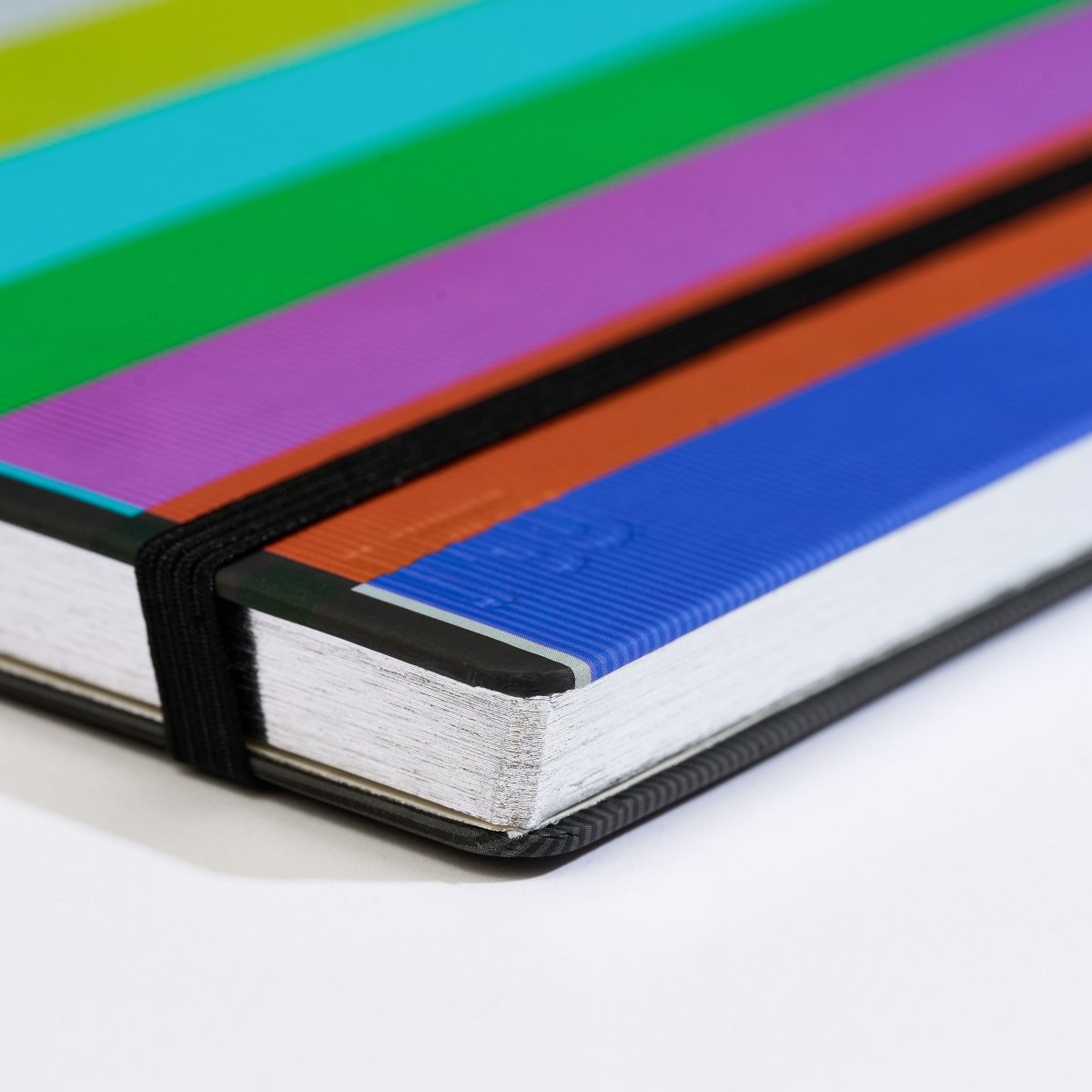 Close-up of a hardcover notebook with a colorful striped cover on a white background