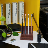 Solid wood pencil stand holding four Blackwing pencils