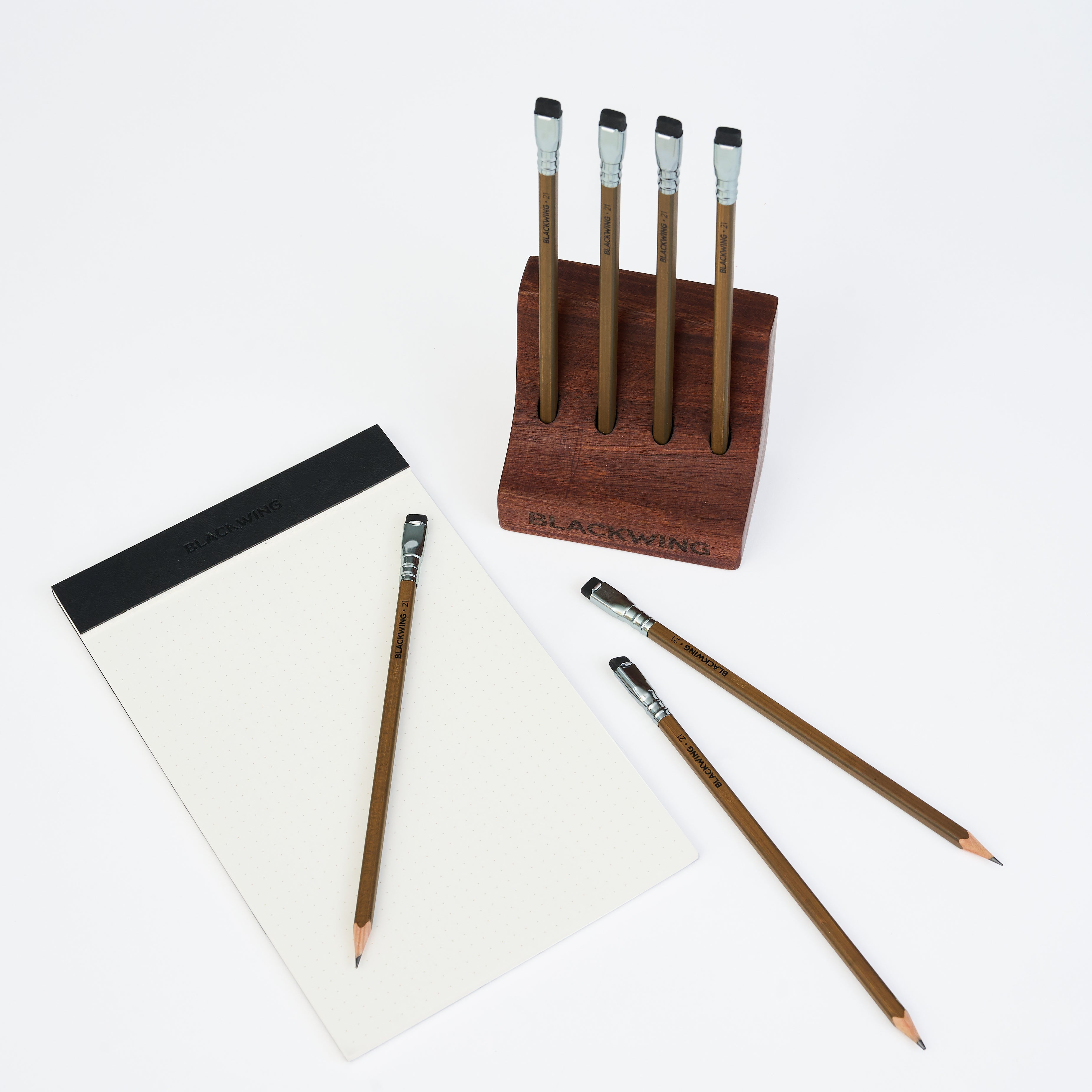 blackwing pencils and a legal pad on a white surface with a wood pencil display