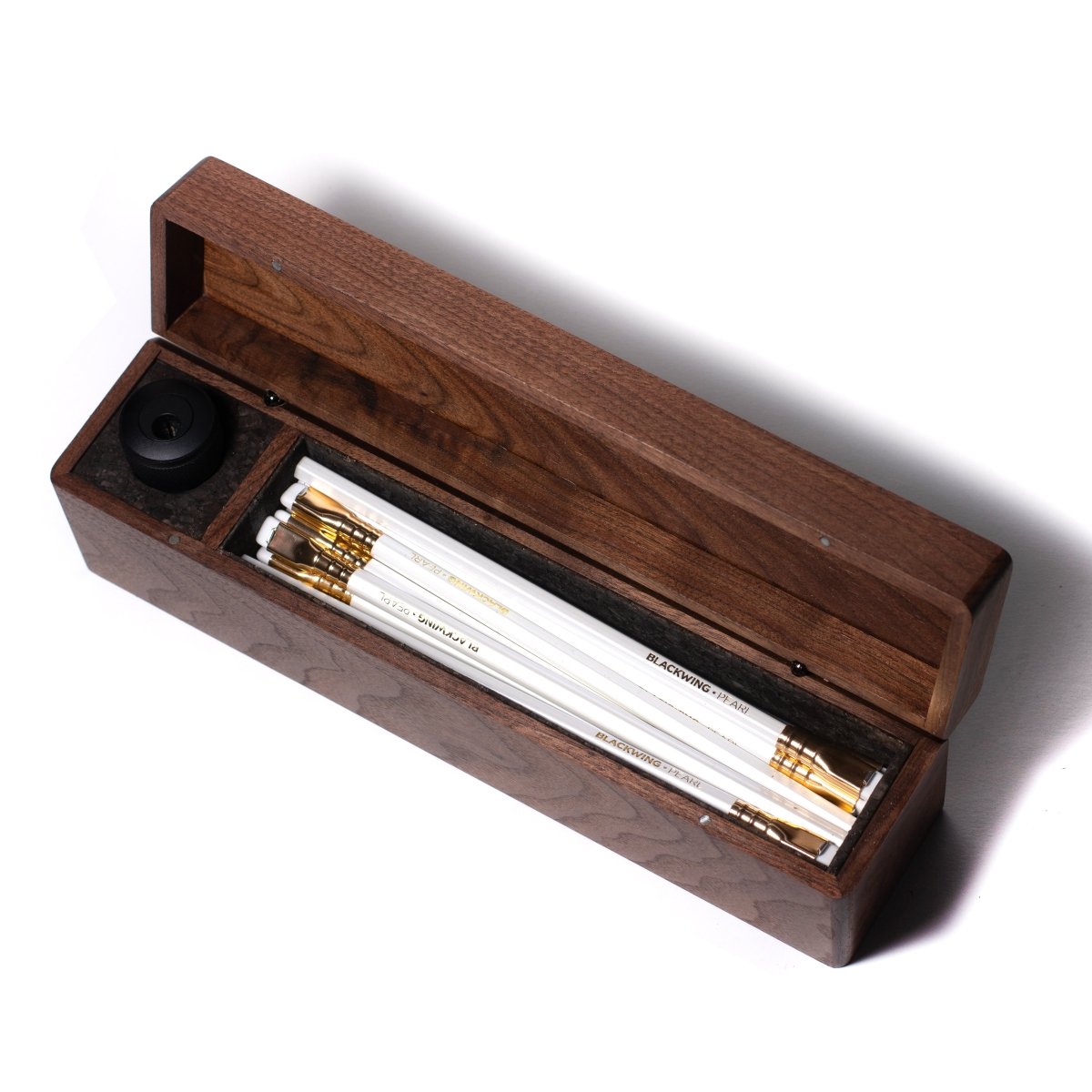 A Blackwing Walnut Box filled with Blackwing pearl pencils and pens.